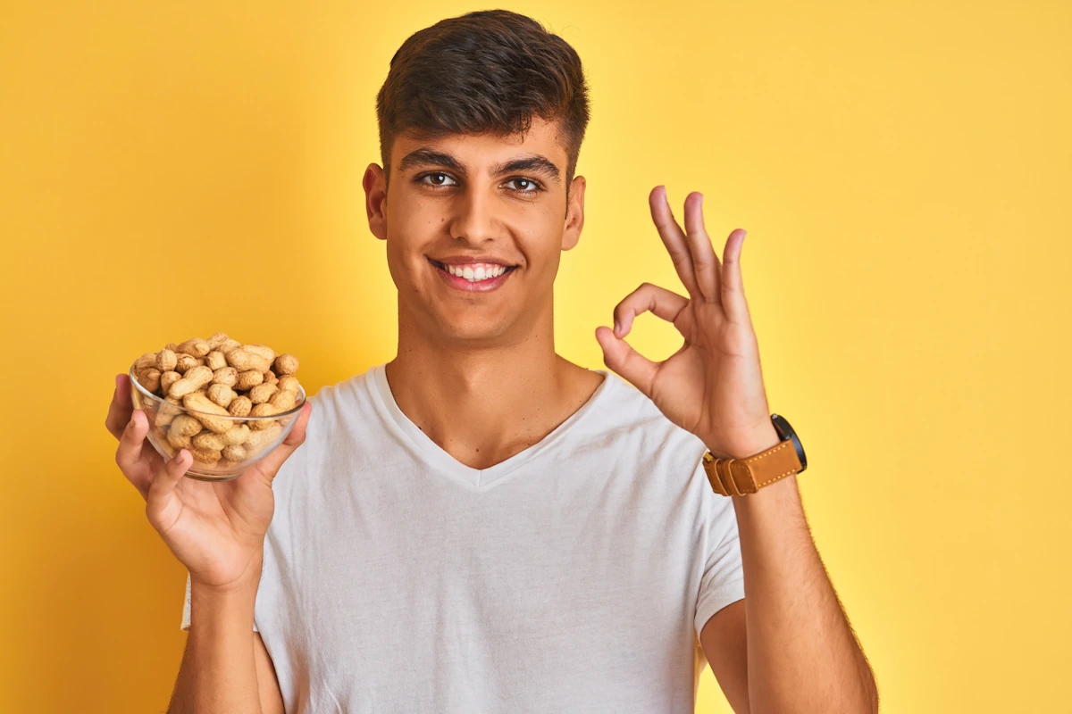 Un jeune homme qui tient un bol de noix de cajou