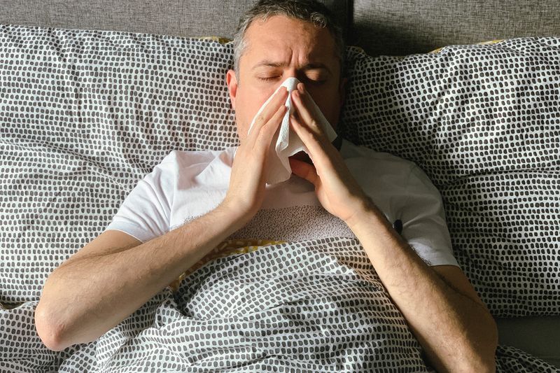 adult male suffering from cold in bed