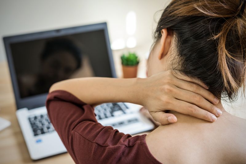 adult woman massaging her neck at work