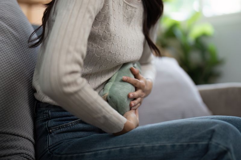 woman seated with warm compress on abdomen