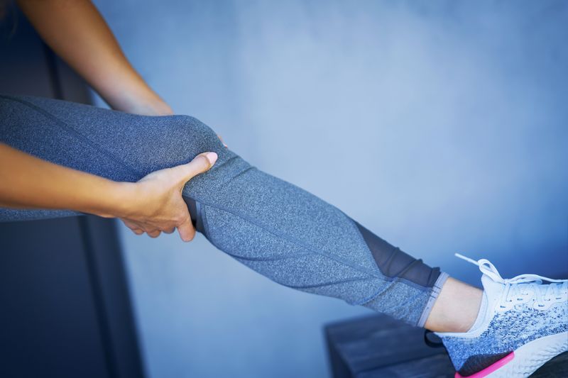 woman stretching leg while touching knee