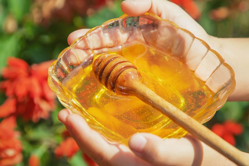 child holds bowl of honey in garden