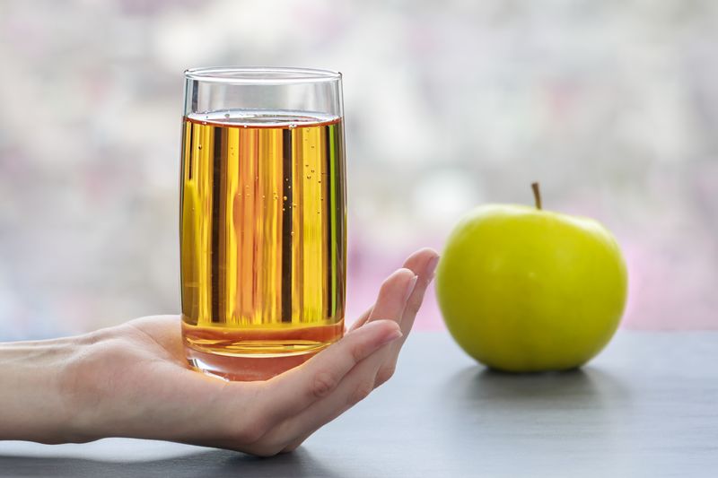 glass of apple juice with green apple nearby