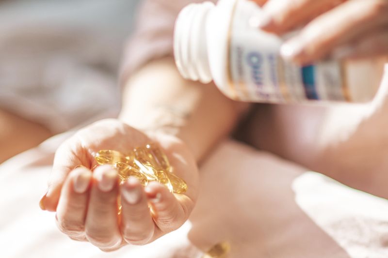hand holding omega 3 fish oil pills from bottle