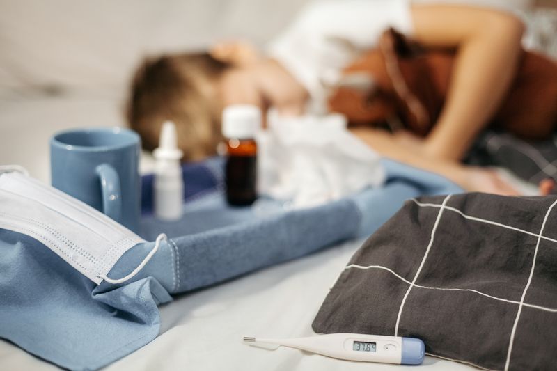 ill child resting with thermometer and medicine