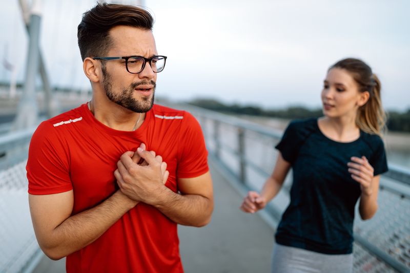 man experiencing chest pain while running with wom