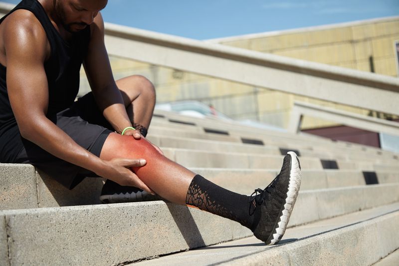 man on stairs holds aching knee