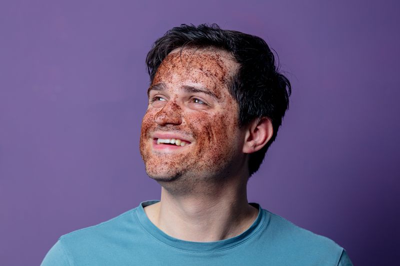 man smiling with a facial mask treatment
