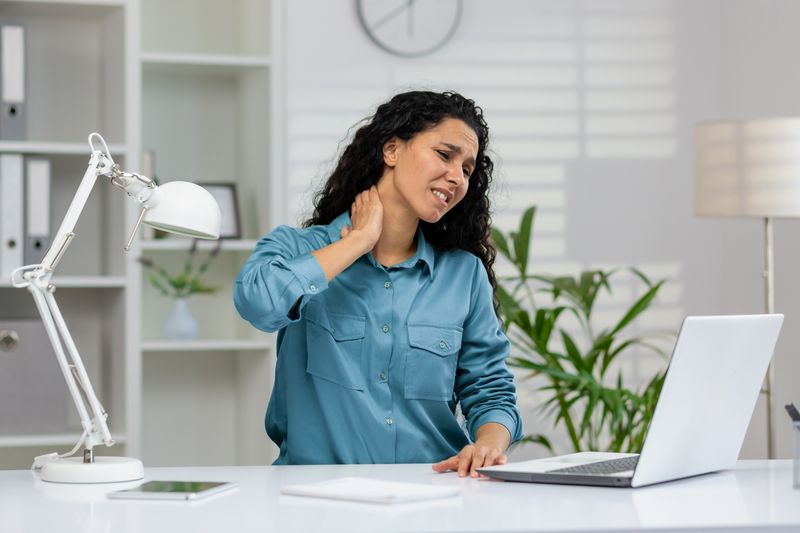 office worker experiencing neck pain while using l