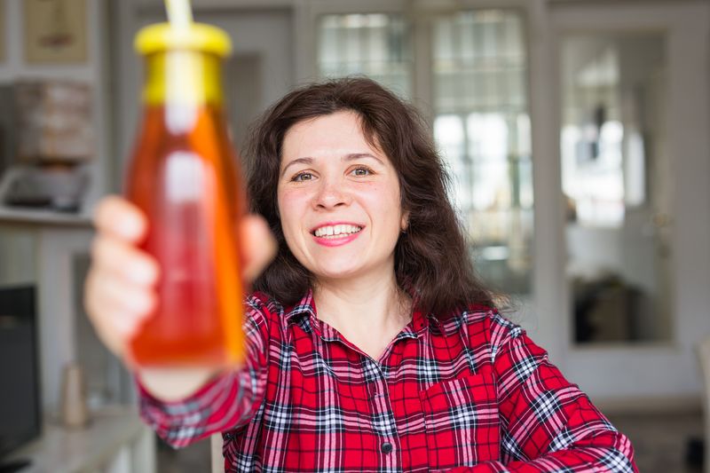 smiling woman holding a bottle of refreshing juice