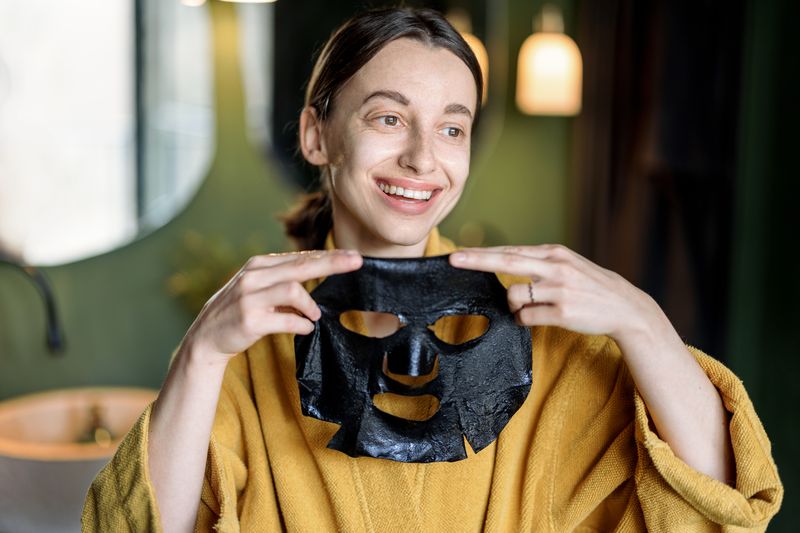 smiling woman with black facial mask in bathroom