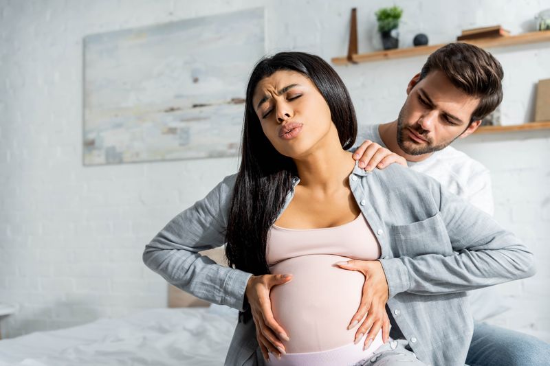 supportive partner massaging shoulders of pregnant