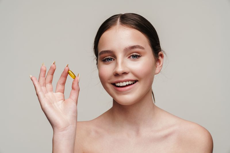 teenage girl holding a vitamin capsule smiling