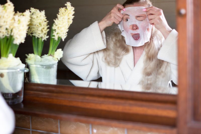 woman applies funny face mask in the bathroom