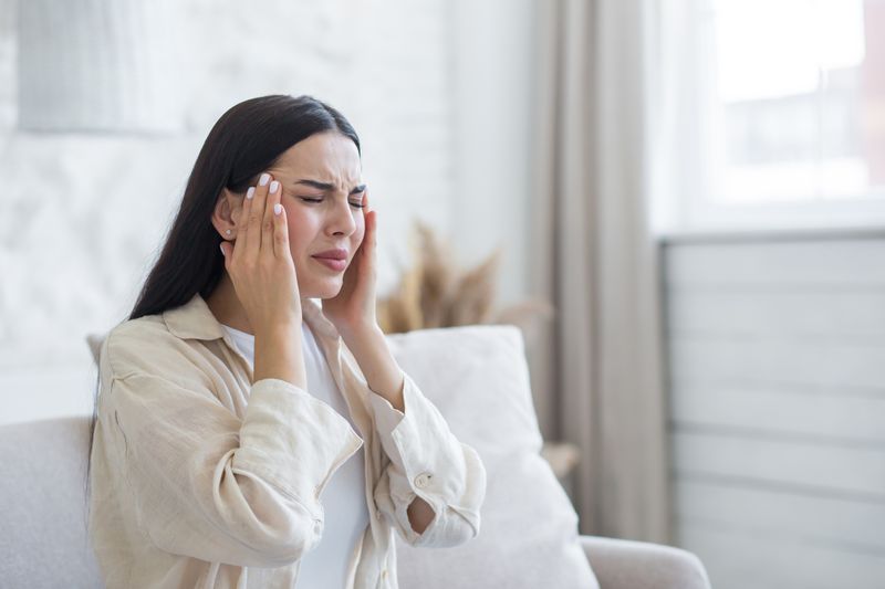 woman experiencing headache at home on the couch
