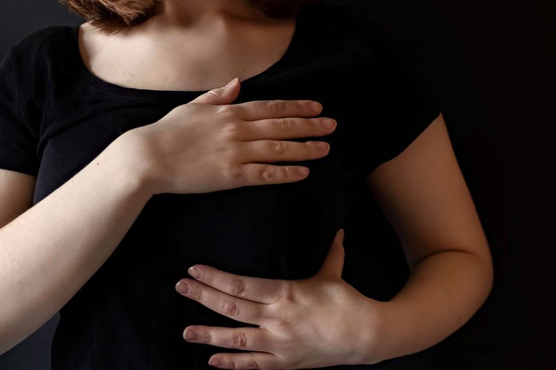 woman holds her chest and stomach region