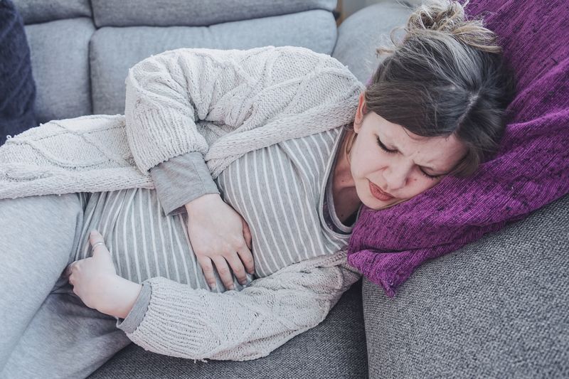 woman lying on couch with hands on stomach