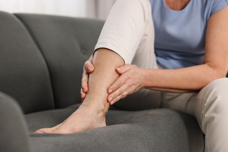 woman massaging leg while sitting on sofa