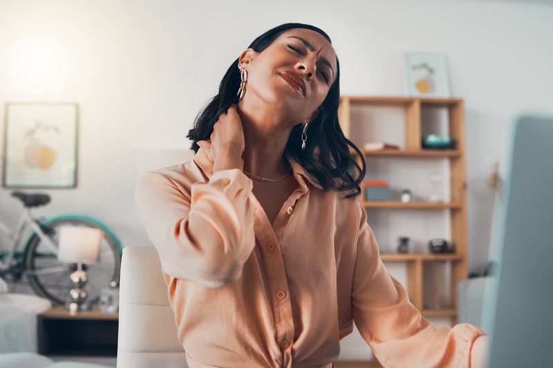 woman massaging neck in home office setting