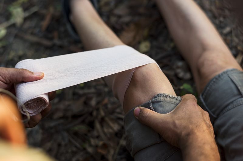 wrapping injured leg with bandage outdoors